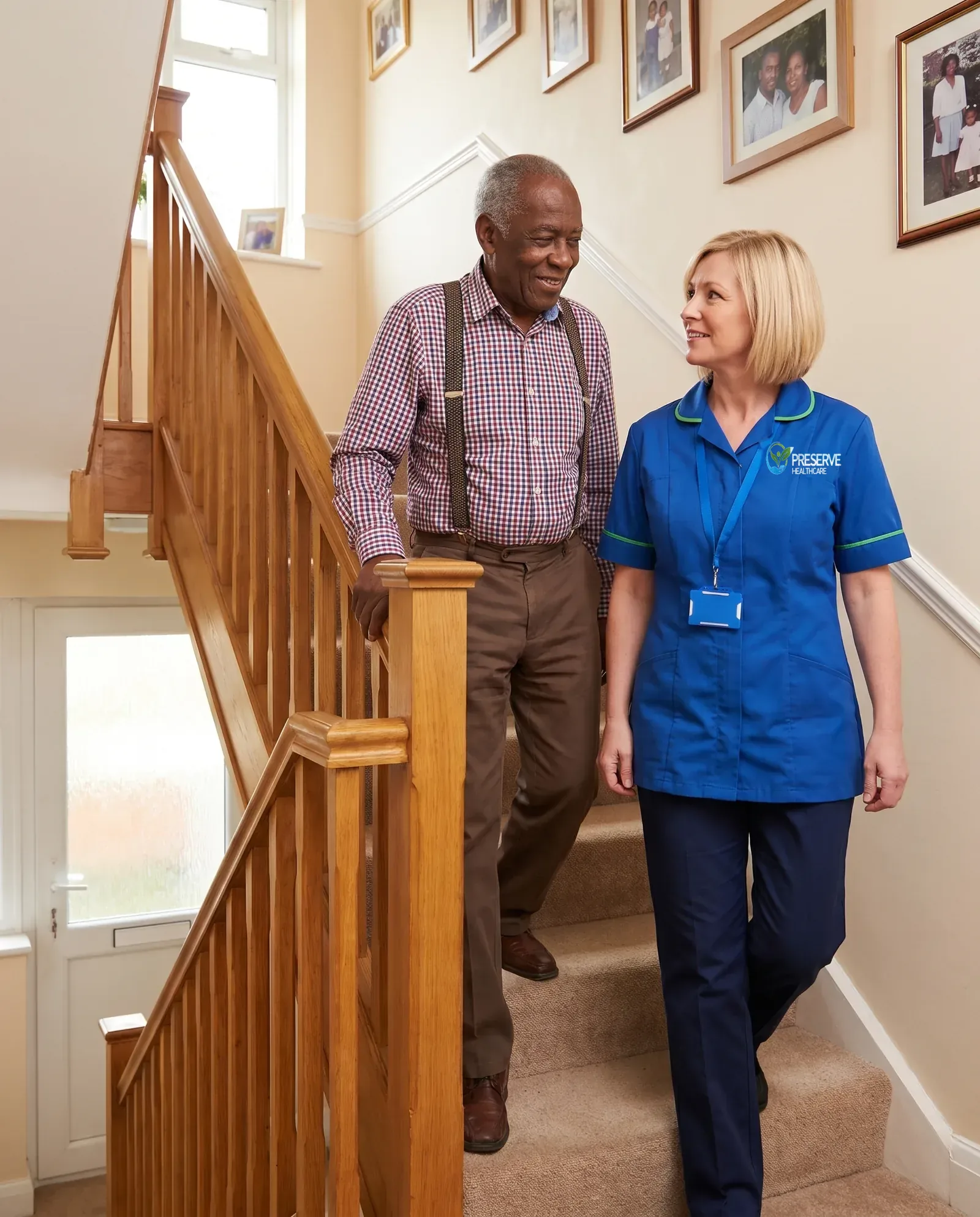 Carer walking behind an older man as he climbs the stairs at home with confidence