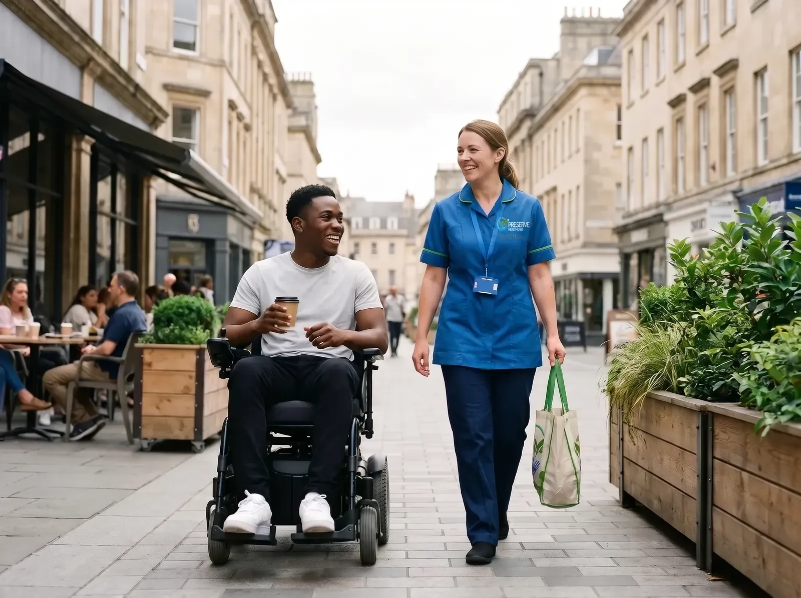 Young man using a power wheelchair out shopping in Coventry city centre with a carer beside him